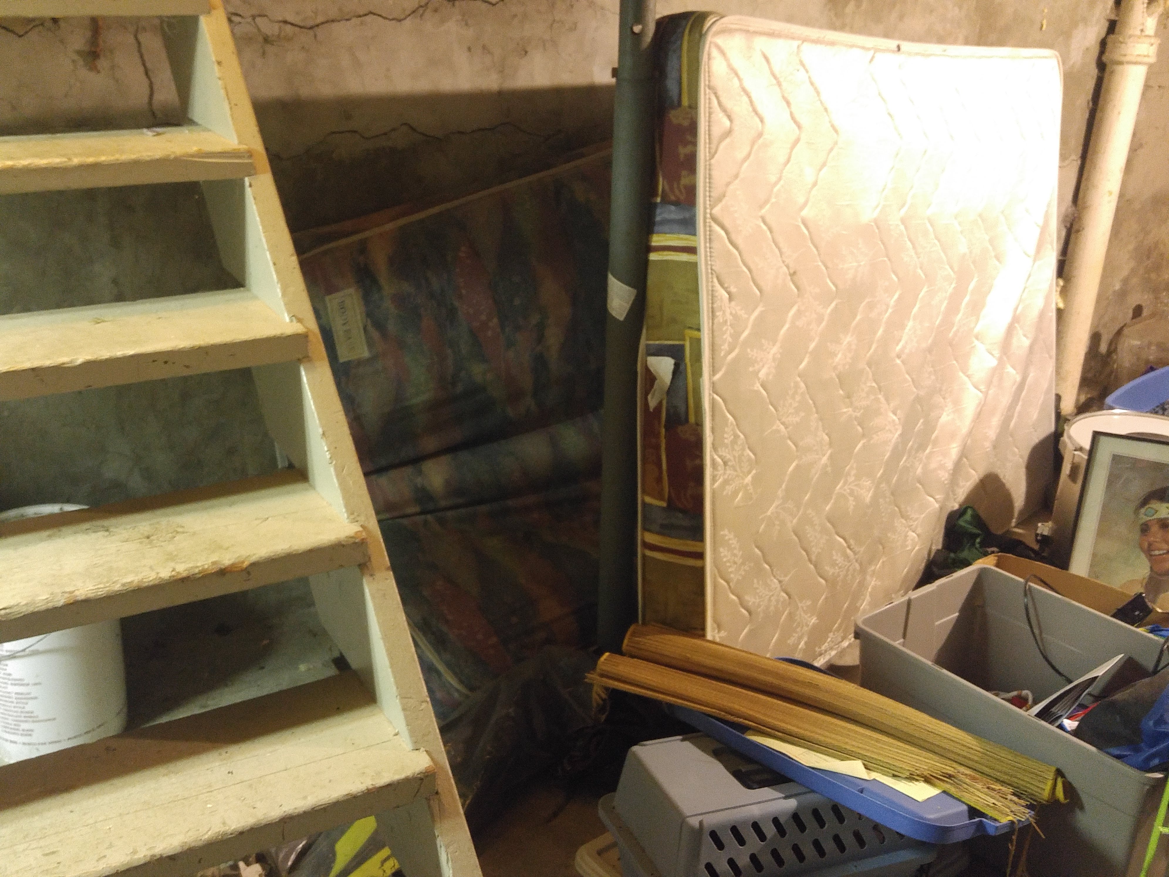 Mattresses and belongings piled up near a wall.
