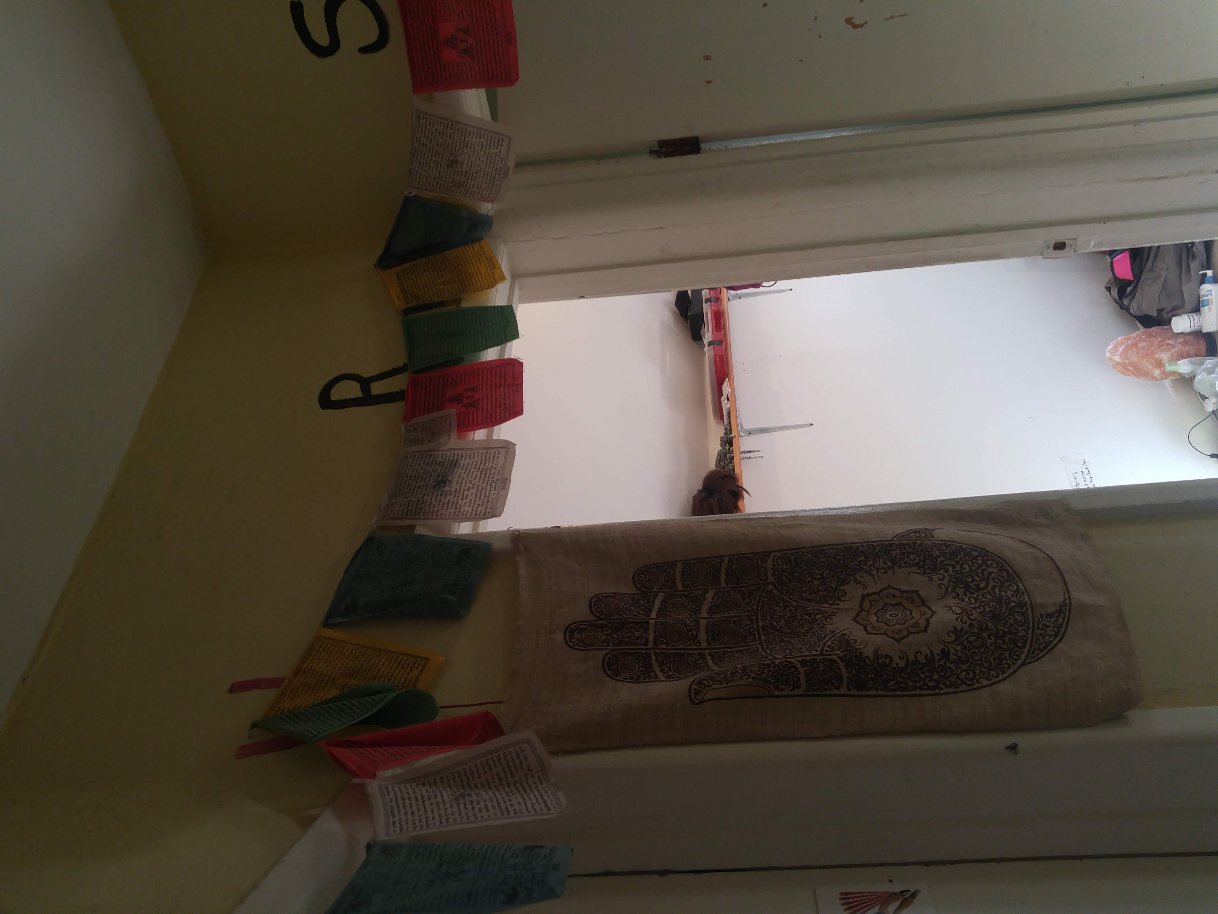 Looking at one of the doors and prayer flags. A large hansa hand wall hanging is between two doors.
