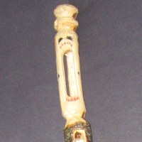 The head of the hiking staff, carved hollow with the opening creating a screaming face.