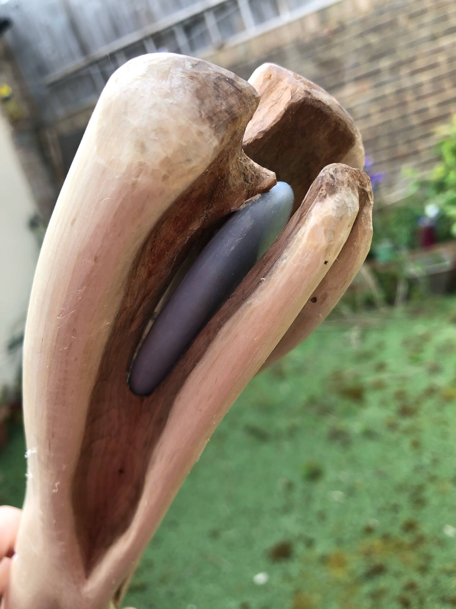 The head of the staff, with an extra curved horn of wood added to curve slightly overtop of the stone to lock it into place, and a small piece of white leather is visible between the stone and the wood to keep it from rattling as you walk with it.