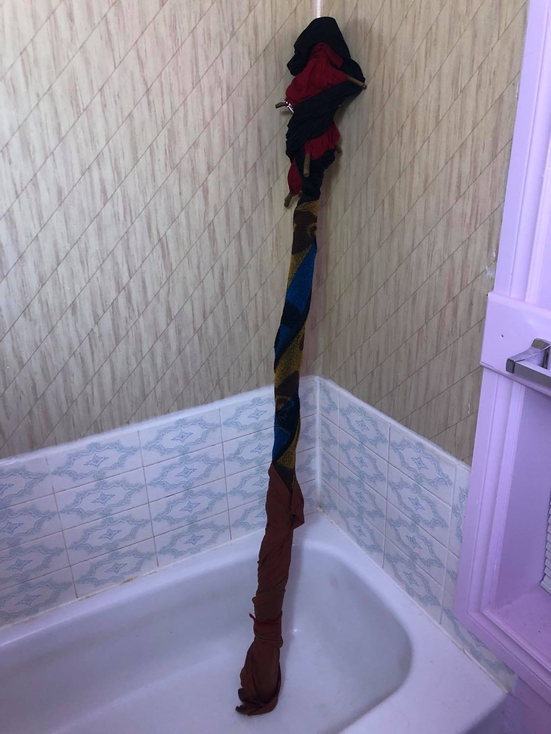 The staff wrapped in some old black and red tshirts and a towel, soaking wet, sitting in the corner of the bathtub to darken.