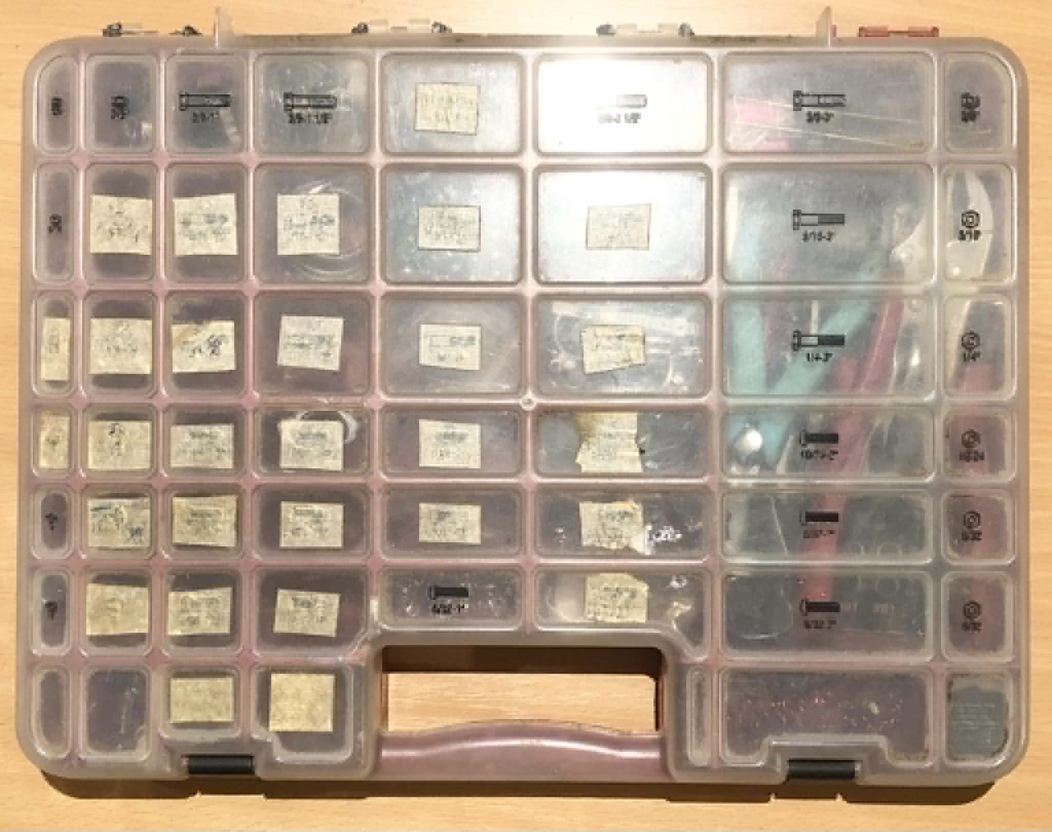 My original chainmailling kit, labelled with barely readable painters tape squares, sitting on a wooden table.