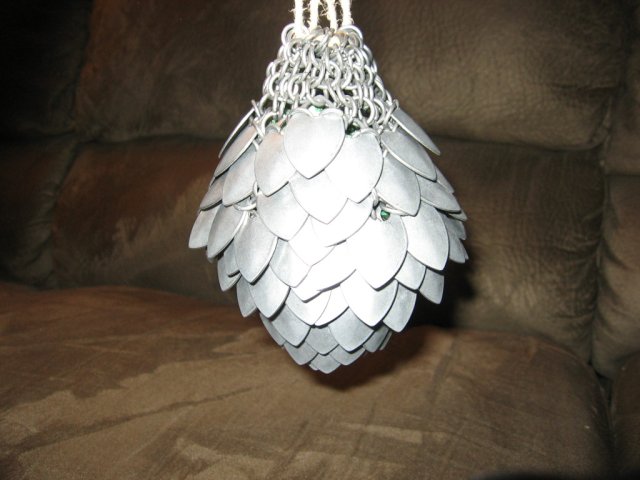 The scalemaille pouch, packed full of dice, and held above a brown couch.