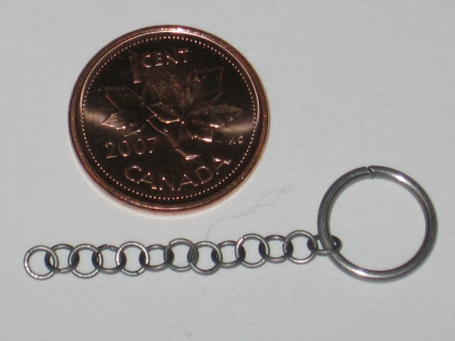 Showing the size of the rings being used, just a bit bigger than the C of Canada on a penny. A small chain of these rings attached to a bigger ring on one end.