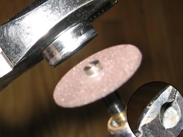 Showing the ring clamped in a pair of pliers, with a dremel cutting wheel in front of it. A cutaway pic shows the edge of the pliers that was ground away from the process.