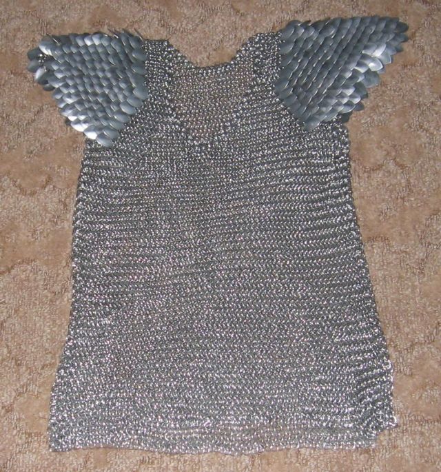 The shirt with scale shoulders, spread flat on a brown carpet.