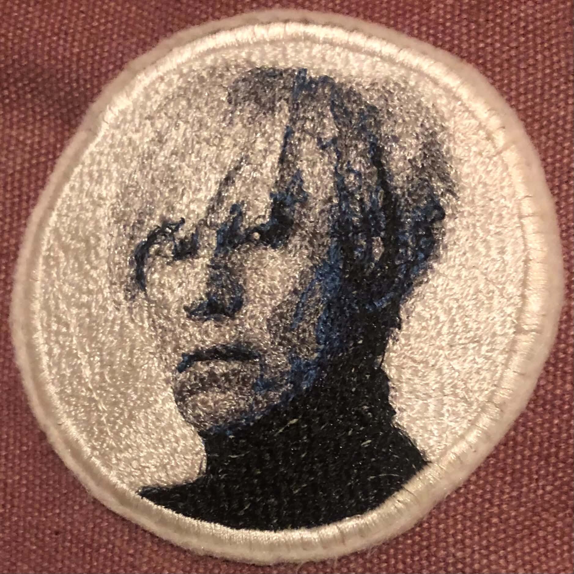 An embroidered patch of Andy Warhol's face on a purple canvas bag