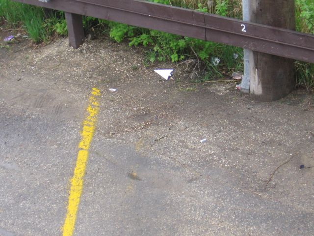 A paper airplane at the end of a parking lot, sitting on the ground.