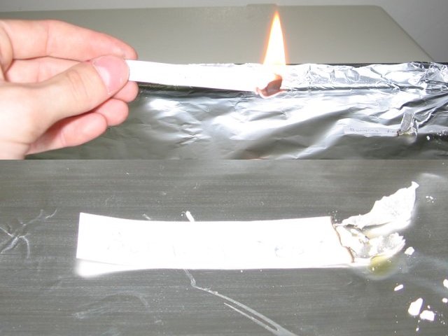 The strip of all weather paper burning with a much larger flame, over twice the size, and a closeup of the strip after it was put out, showing less blackened edge at the burnt tip than the regular paper.