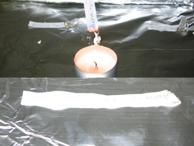 Attempting to burn the regular wet paper, holding it above a lit candle, and showing just a bit of the corner of it burnt.