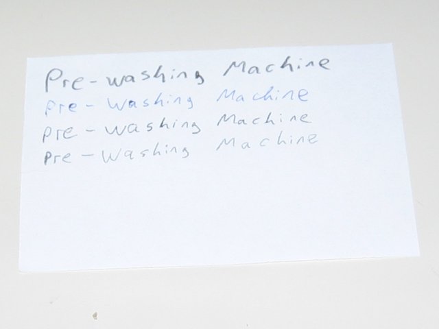 A larger rectangle of paper with pre-washing machine written on it in the four writing utensil types.