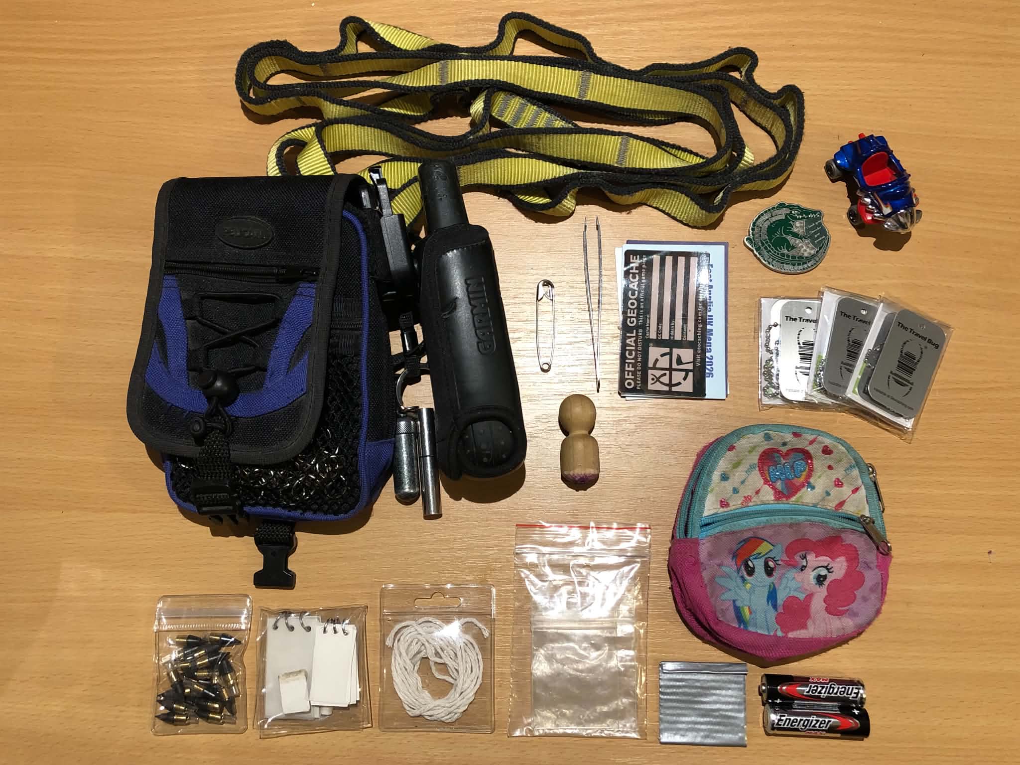Kabutroid's geocaching bag, fully unpacked and displayed on a wooden table.