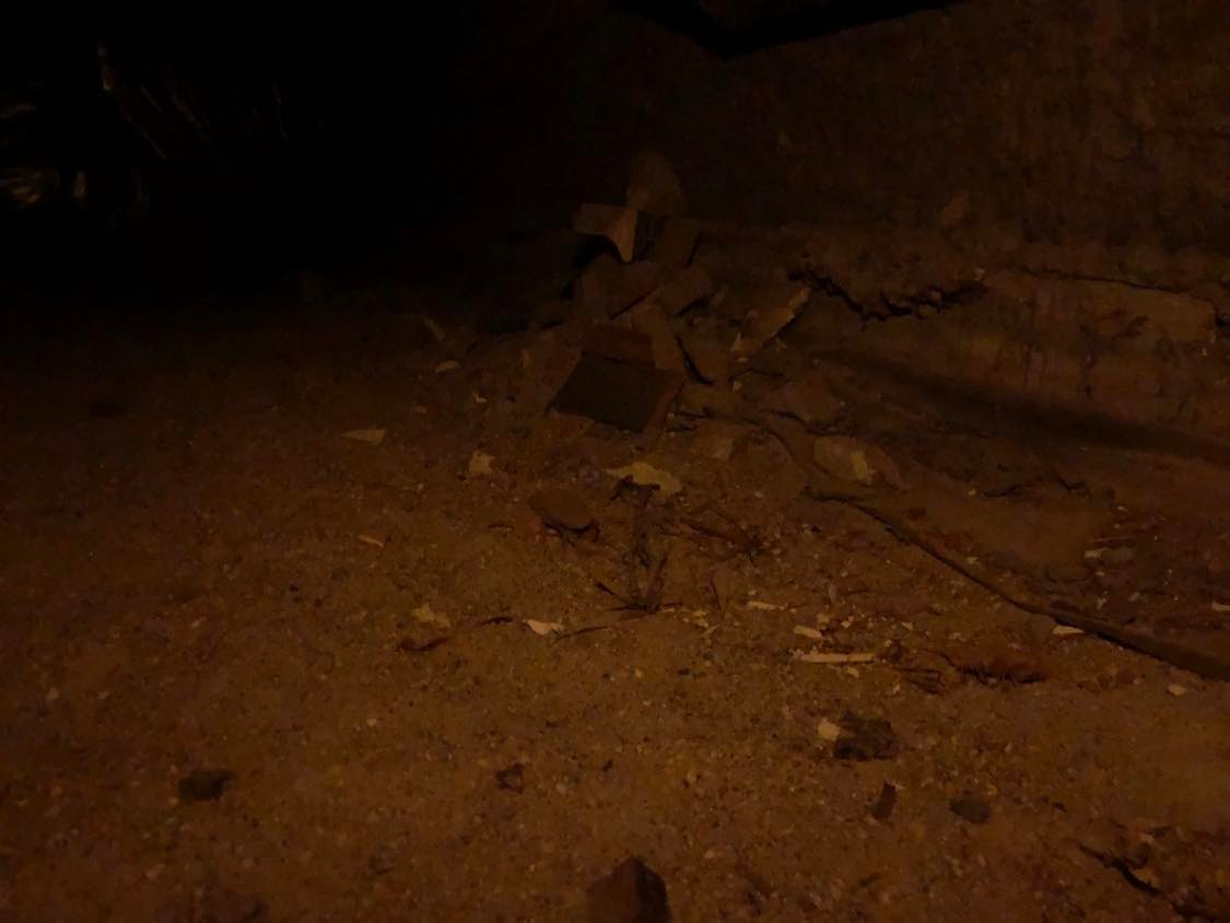 A rough pile of rocks, barely visible on the dirt and sand.