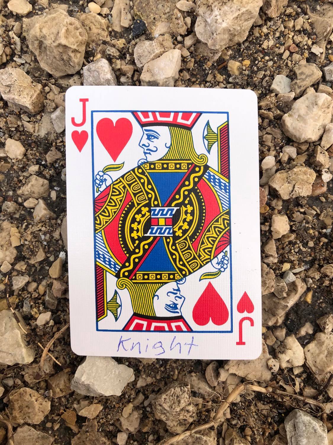 The jack of hearts with Knight written on it, laying on the gravel path.