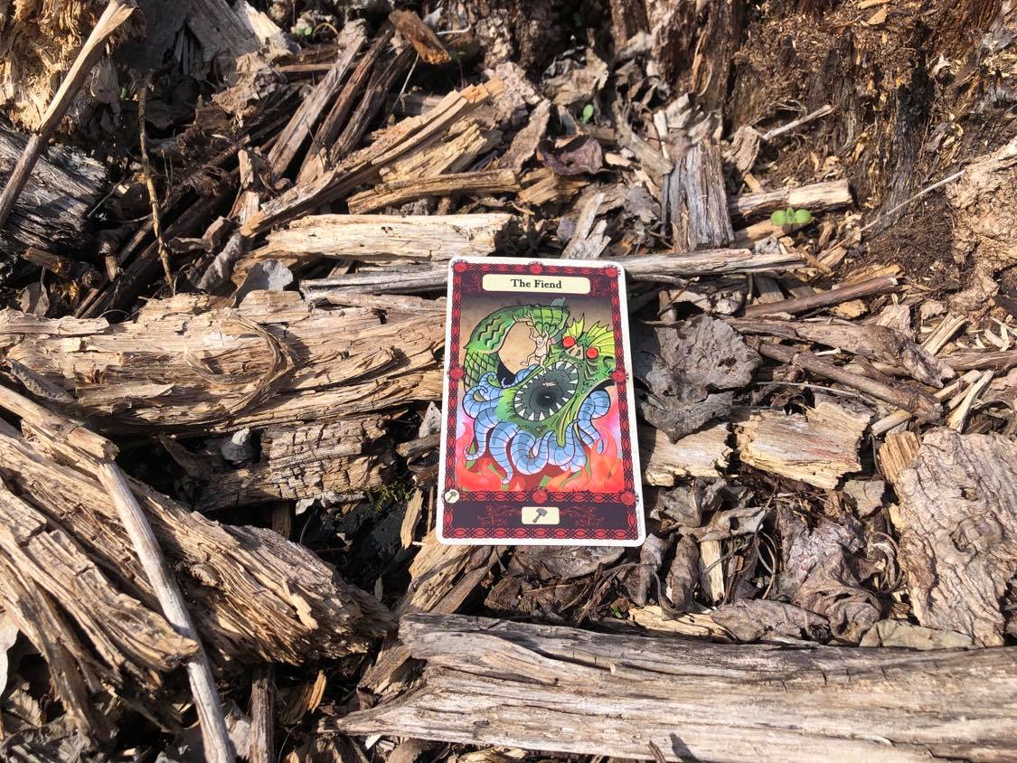 A sea monster eating a person, the card laying on the forest debris.