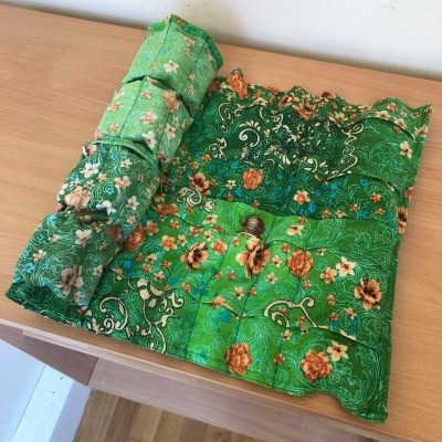 A partially rolled scroll of floral green fabric, filled with potion bottles.