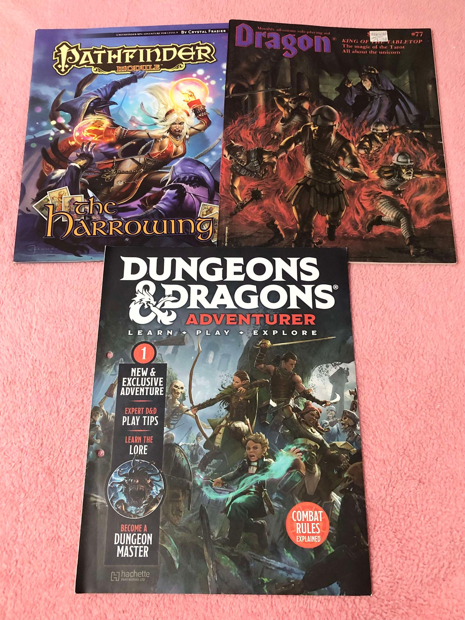 Three magasine style books on a blanket, the first is The Harrowing module for Pathfinder, Dragon magasine 77, and Dungeons and Dragons adventurer issue 1!