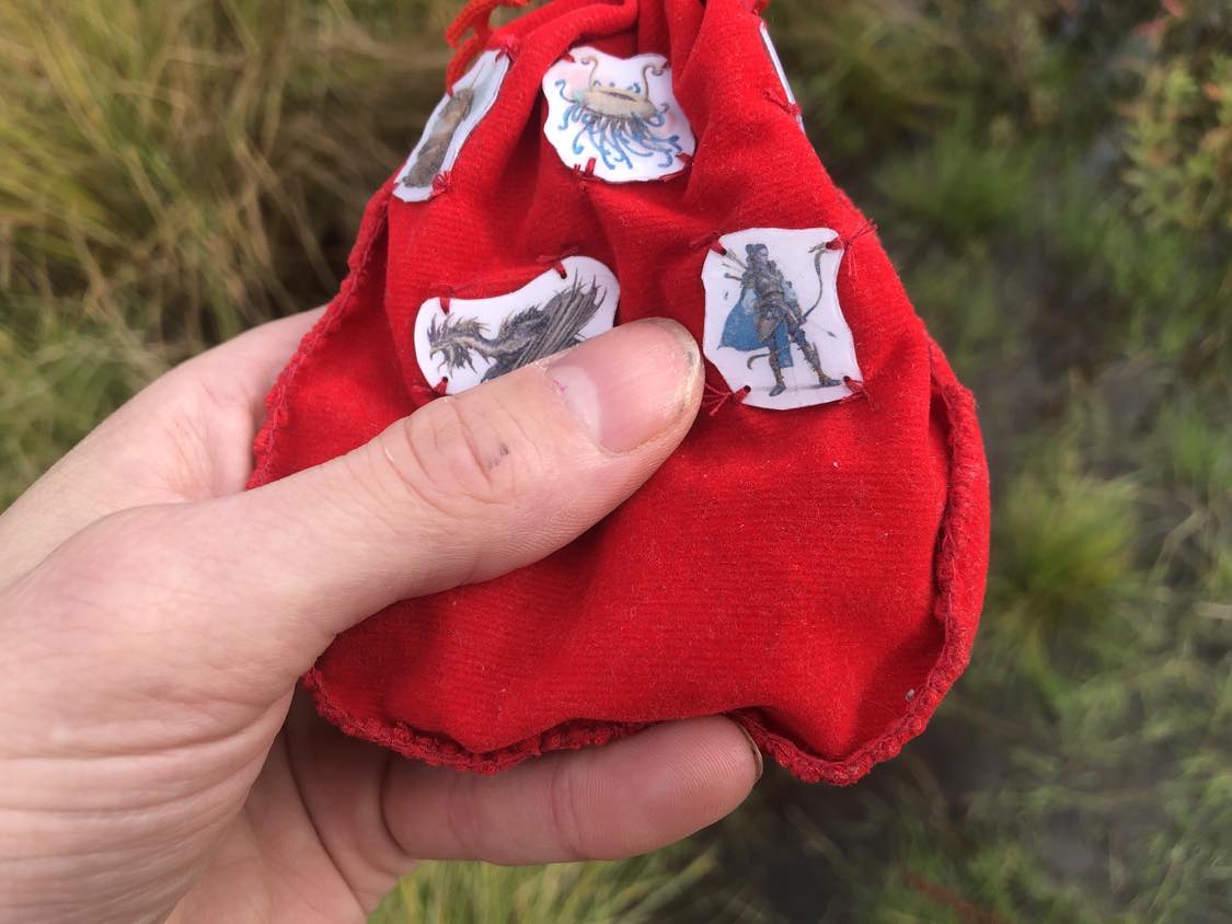 The pouch held close, feeling around at the contents inside, images of a cockatrice, a ranger, and a flumph readily showing on the bag.